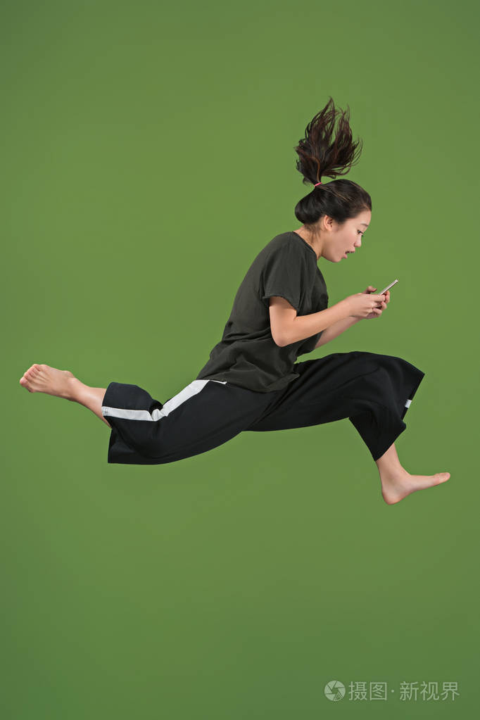 自由移动.漂亮的年轻女子跳反绿色背景