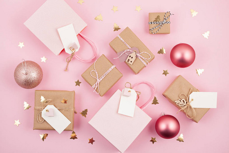平躺现代极简主义圣诞礼物和木制圣诞装饰粉红色背景。