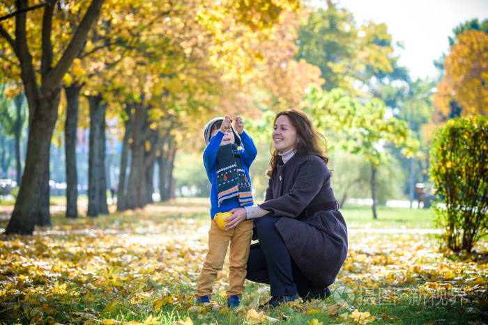 父母和孩子在阳光明媚的秋天在森林里散步.