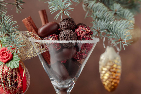 高脚杯里各种精致的巧克力糖果。用肉桂棒和巧克力做圣诞装饰。圣诞节的静物生活。