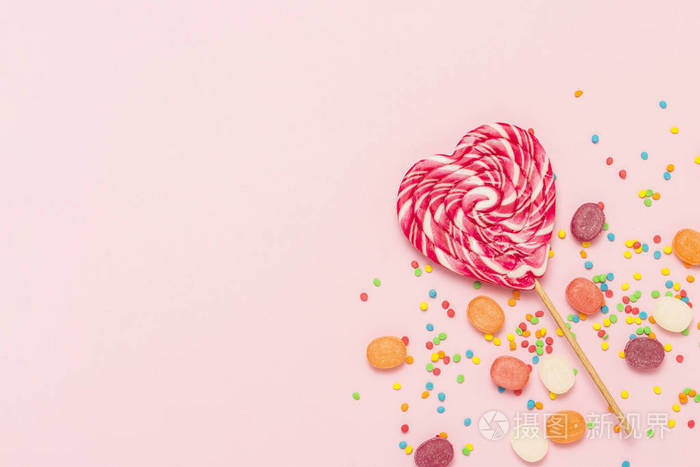 心棒糖和多种颜色的糖果在轻轻的粉红色背景. 糖果和糖果的概念.