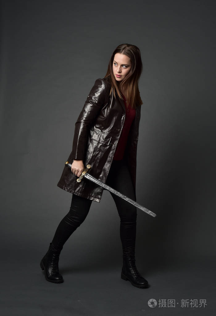 站立姿势,手持剑在灰色工作室背景.