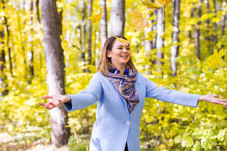 季节, 自然和人概念在公园里玩秋天树叶的年轻女子