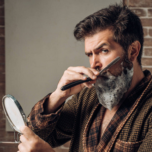 男人在浴室里剃胡子。理发店的概念。胡子蜡。美发沙龙和理发复古