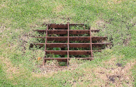 草坪排水系统上的下水道篦子照片