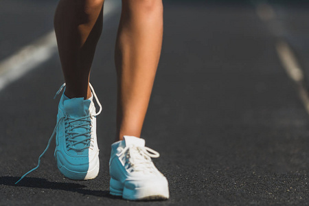 外在的身体年轻女子腿在白色鞋子站立在体育场跑道在夏季天.