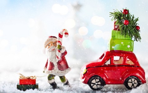 圣诞老人和红色玩具车在雪地景观中携带圣诞礼物。 带有复制空间的圣诞节概念。