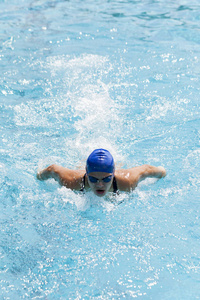 一个年轻的女人在游泳池里游泳，选择专注和小的视野深度。