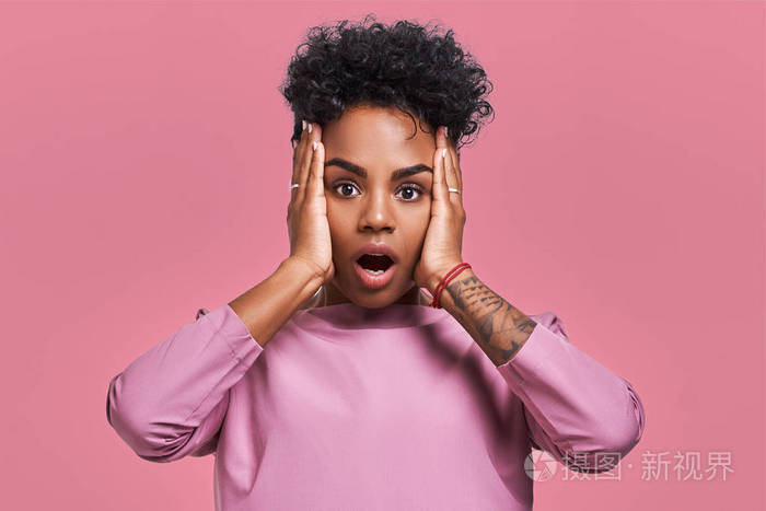 年轻可爱的深色皮肤的女性有卷发, 惊讶地看着镜头, 不停地垂下下巴