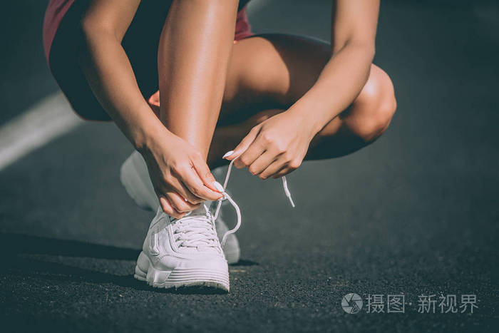 女子手绑鞋带在体育场.准备跑步.快关门前视图