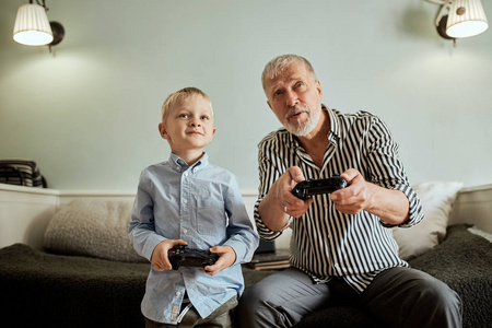 祖父和孙子玩游戏在计算机上的操纵杆
