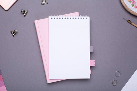 白色记事本与粉红色的书，灰色背景，老式风格，顶部视图。
