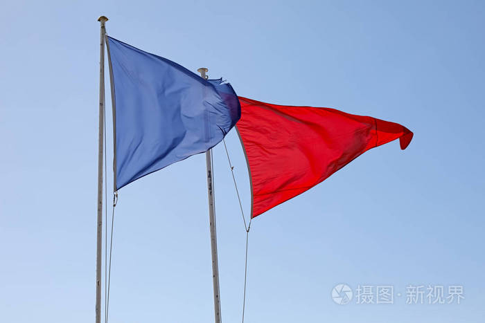 两个三角形的旗帜放置在彼此旁边的桅杆吹在风中以警告和信息的目的
