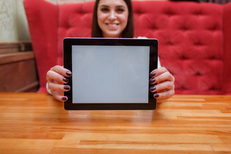一个年轻快乐的女人在咖啡馆的触摸屏平板电脑上交流。现代技术