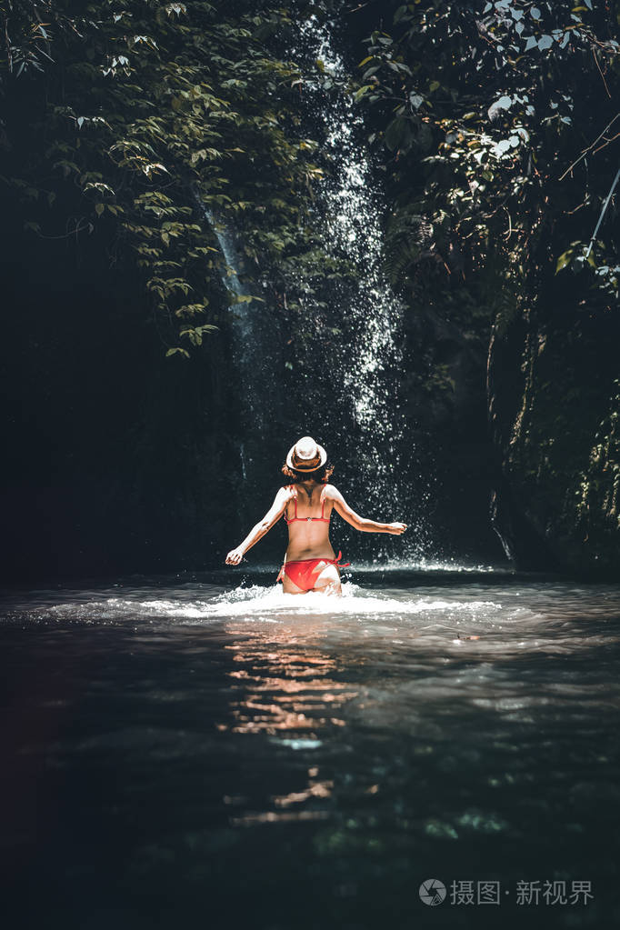 后视图的年轻女子游客在深丛林与瀑布。真正的冒险概念。巴厘岛