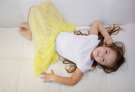 累懒的小女孩躺在沙发上在家.沉睡的孩子休息放松在沙发上照片