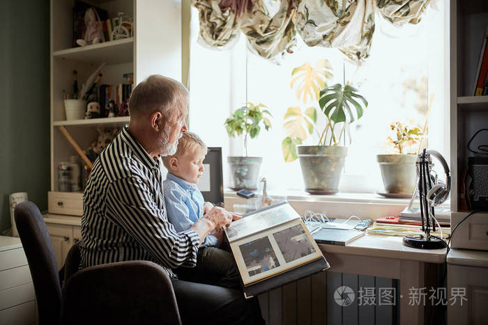 爷爷和孙子在沙发上在家爷爷和孩子看老照片