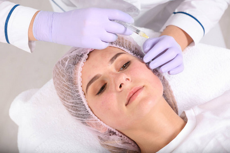 在沙龙特写中接受面部生物数字化手术的妇女。 化妆品治疗