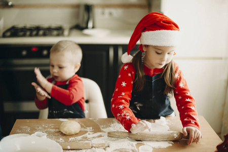 婴儿男孩和女孩用擀面杖在一起，一起准备圣诞饼干