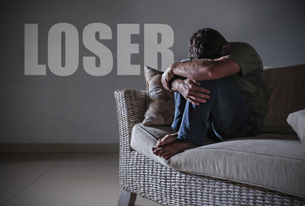 用墙上的失败者这个词哭泣,感到痛苦和失落穿着蓝色衬衣的男人背上