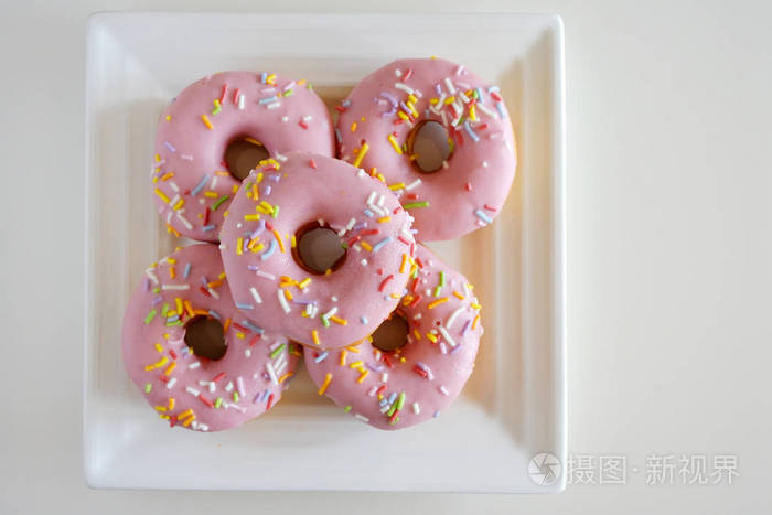 平坦的视野五个甜的粉红色甜甜圈糖果提供在一个方形的白色盘子