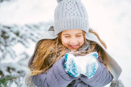 可爱的小女孩微笑着在冬天和雪玩。