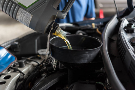 汽车修理工或维修工在汽车修理厂加注新润滑油发动机油，修理或保养汽车