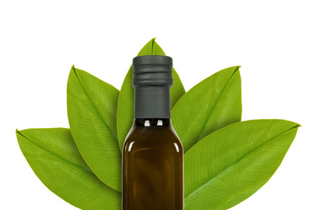 绿叶背景上的绿色橄榄油瓶。 孤立在白色上。 自然起源的概念。
