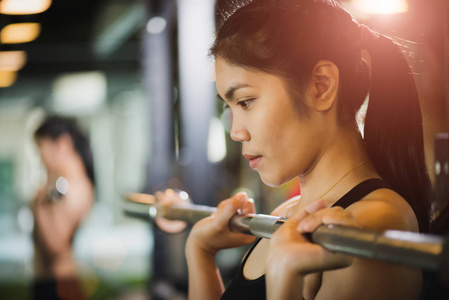 强壮的年轻亚洲女人，用杠铃做运动。 健身健身锻炼和健康生活方式理念。