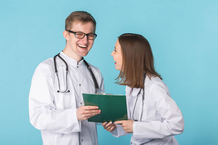 年轻的男性和女性医生笑在蓝色背景