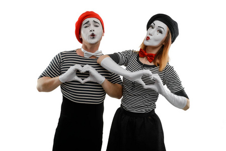 男女哑剧艺术家模仿浪漫的心情,用手显示心形. 爱在空中.照片