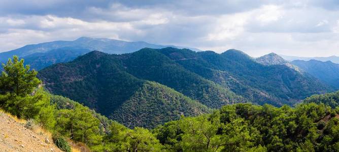 图洛多斯山脉的Kykkos修道院地区的全景，在多云的天空前有青山和松林