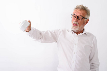 摄影棚拍摄的英俊大胡子男子拿着空咖啡杯倒着，戴着白色背景的眼镜