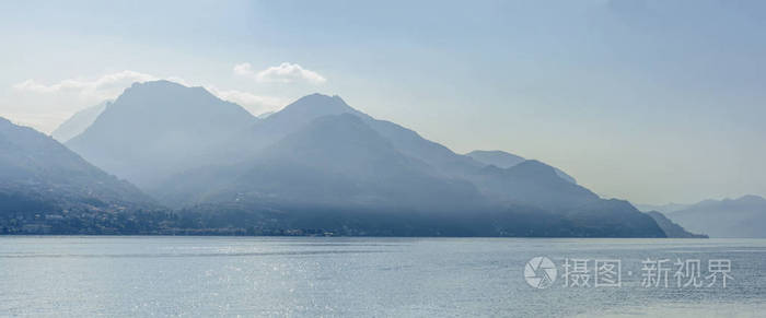 从意大利圣西罗的明亮的落光中拍摄的科莫湖上的格里尼亚峰峦景观
