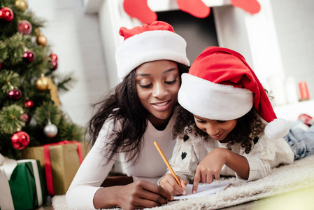 非裔美国人母亲帮助女儿在家给圣诞老人写信