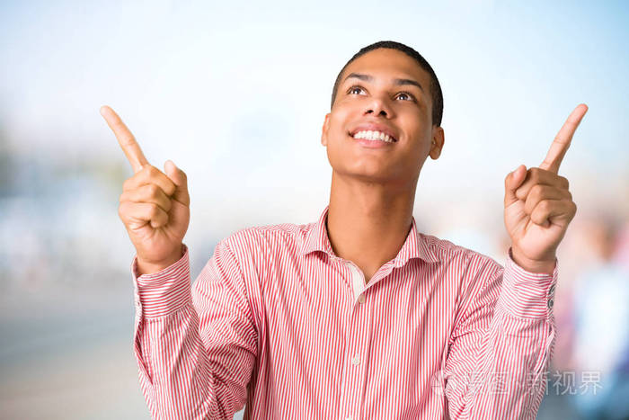 年轻的非裔美国人用食指指着一个伟大的想法抬头看不集中的户外背景