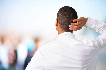 年轻的非裔美国男人,背着白色衬衫,回头看,在没有聚焦的户外背景上