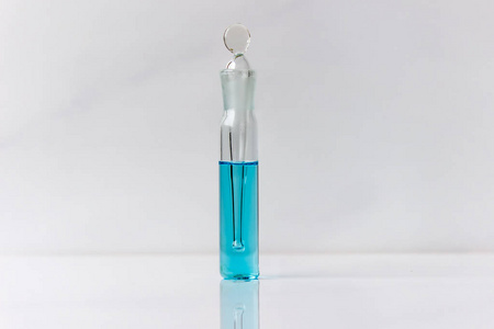 硫酸铜溶液在一个小容器中。 白色背景上分离的玻璃器皿中的蓝色液体。