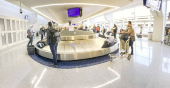 全景模糊了在达拉斯沃斯堡国际机场行李提取区等待行李的各种乘客。传送带上背景各种手提箱的离焦
