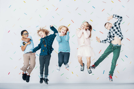 微笑的多元文化儿童群体在彩色壁纸上跳跃照片