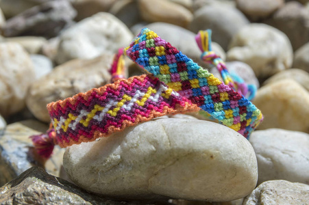 友谊的天然手镯在一排五颜六色的编织友谊手镯背景彩虹颜色格子图案