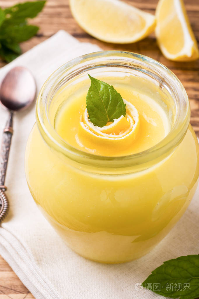 自制柠檬凝乳在玻璃瓶与新鲜柠檬乡村木制背景复制空间