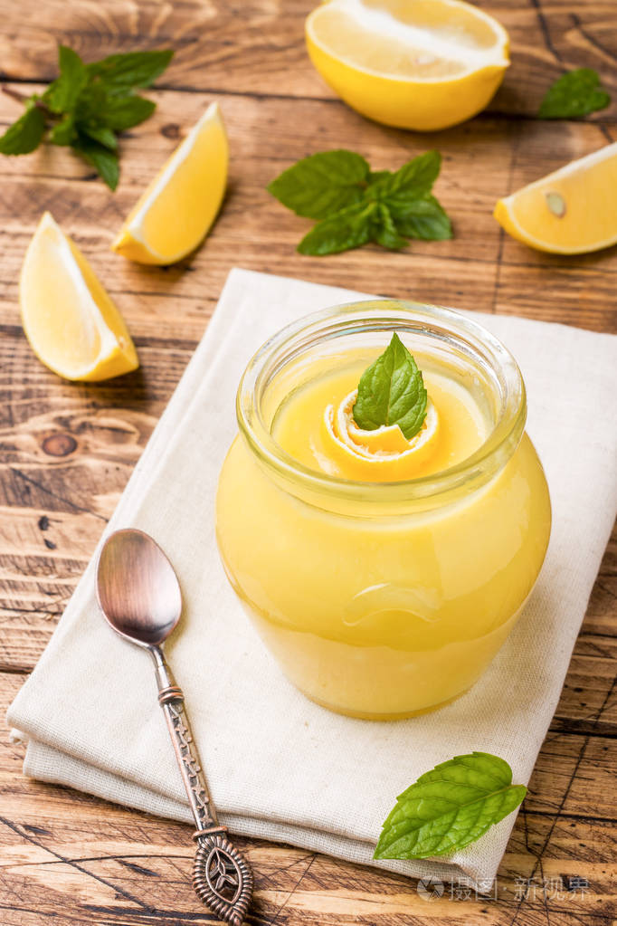 自制柠檬凝乳在玻璃瓶与新鲜柠檬乡村木制背景复制空间