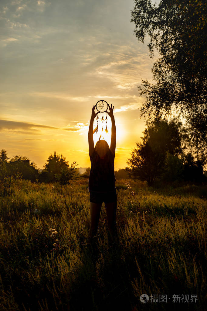 愿望和梦想的守护者羽毛在傍晚的阳光下捕捉梦想和愿望一个女孩的剪影