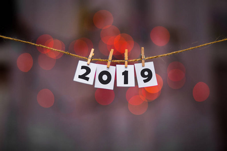 新年快乐，2019年文本与衣架与花环博克背景的论文。 猪年