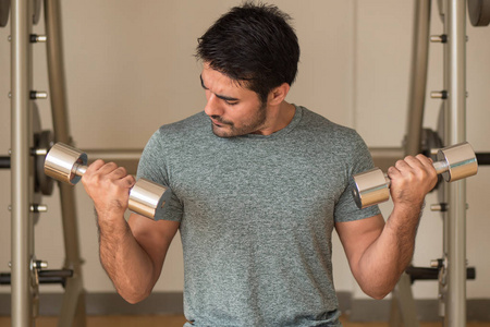  portrait of asian man doing weight training with dumbbell in fi