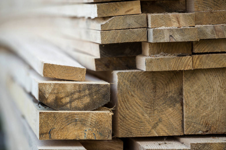 堆叠的天然棕色，不均匀，粗糙的木板，不同大小的横截面视图。 用于木工建筑修理和建筑家具木材材料的工业木材。