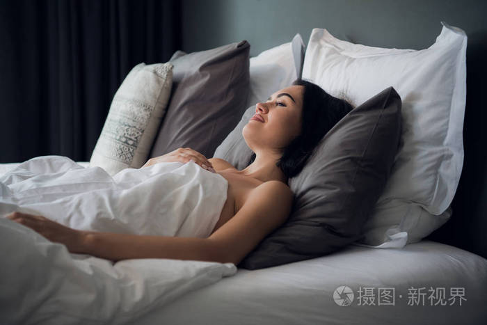 一个年轻可爱的黑发女孩的肖像睡在光客厅的床上她