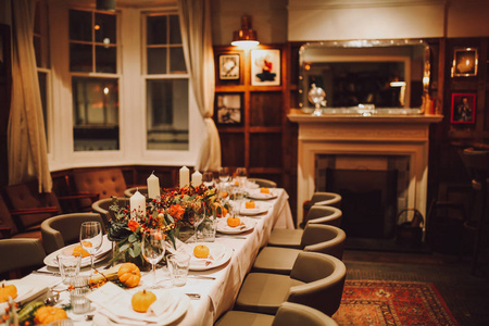 感恩节桌子设置与自动装饰南瓜眼镜和盘子。 假日餐饮和酒店理念。