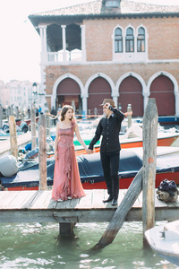 在威尼斯度蜜月期间，一对夫妇在贡多拉斯附近的木墩上摆姿势